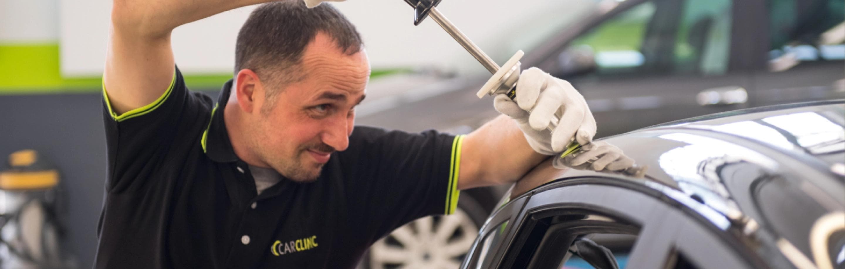 Carrozziere al lavoro durante la riparazione di una carrozzeria